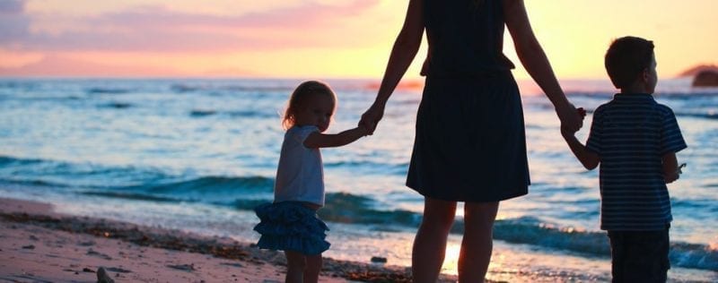 Child Custody FAQ and Answers; woman walking hand in hand with two small children on beach