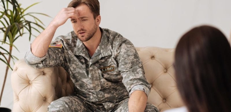 military man looking frustrated sitting on couch talking to woman; military divorce