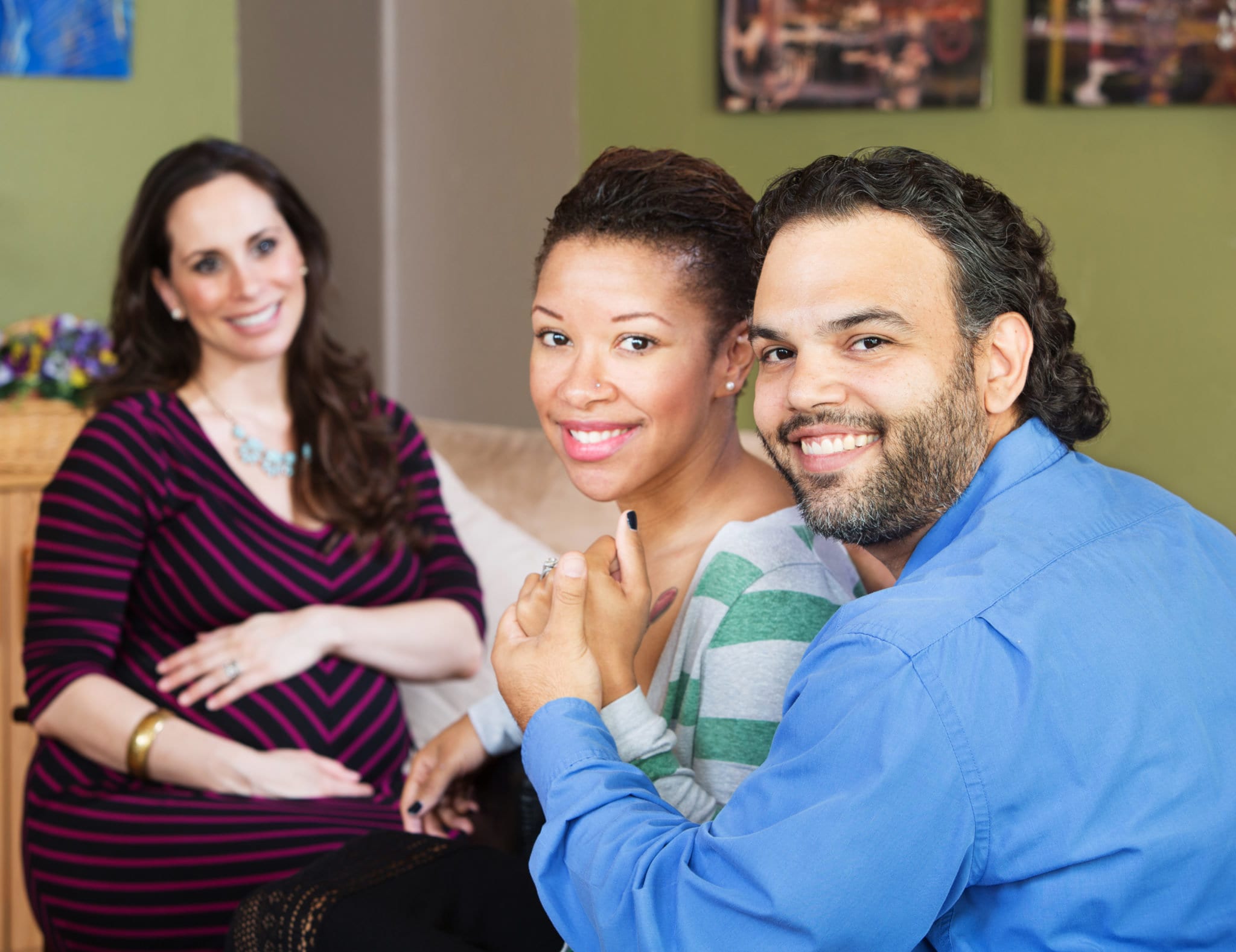 Smiling Hispanic couple sitting with beautiful surrogate mother for IVF